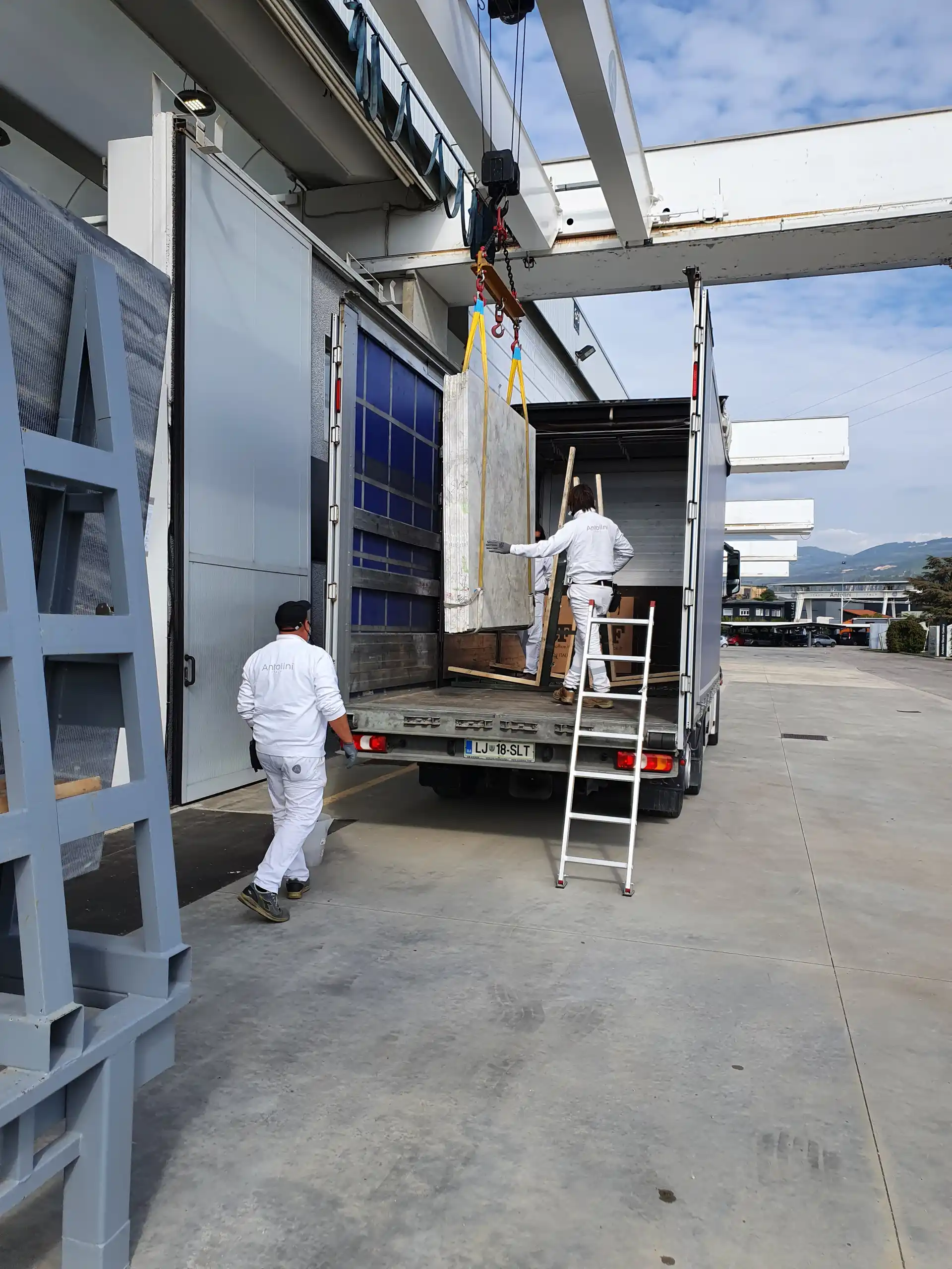 Tracom crew loading a stone slab onto a curtainside truck
